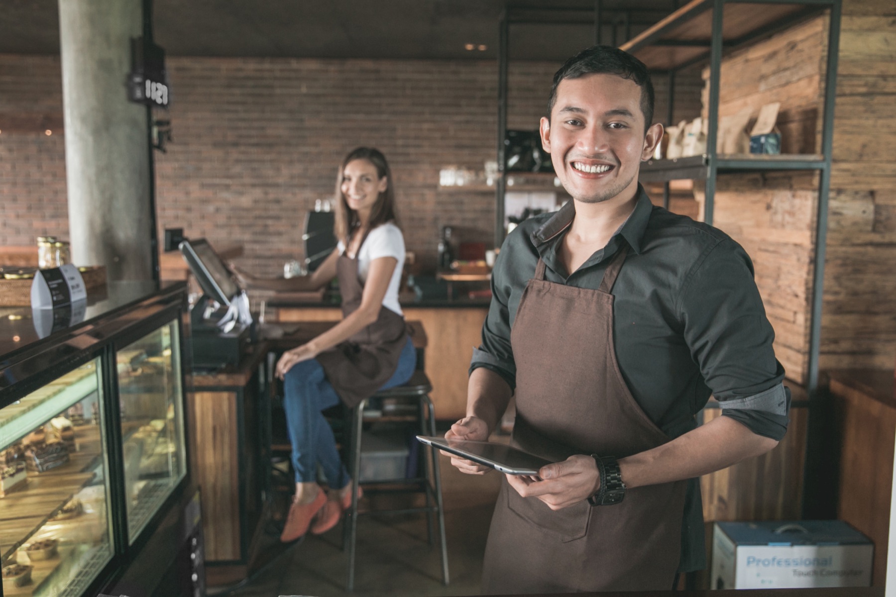 Cafe owner with tablet and team member behind the counter