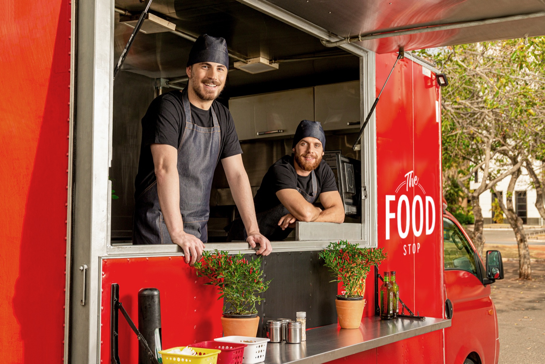 Two chefs serving from a red food truck