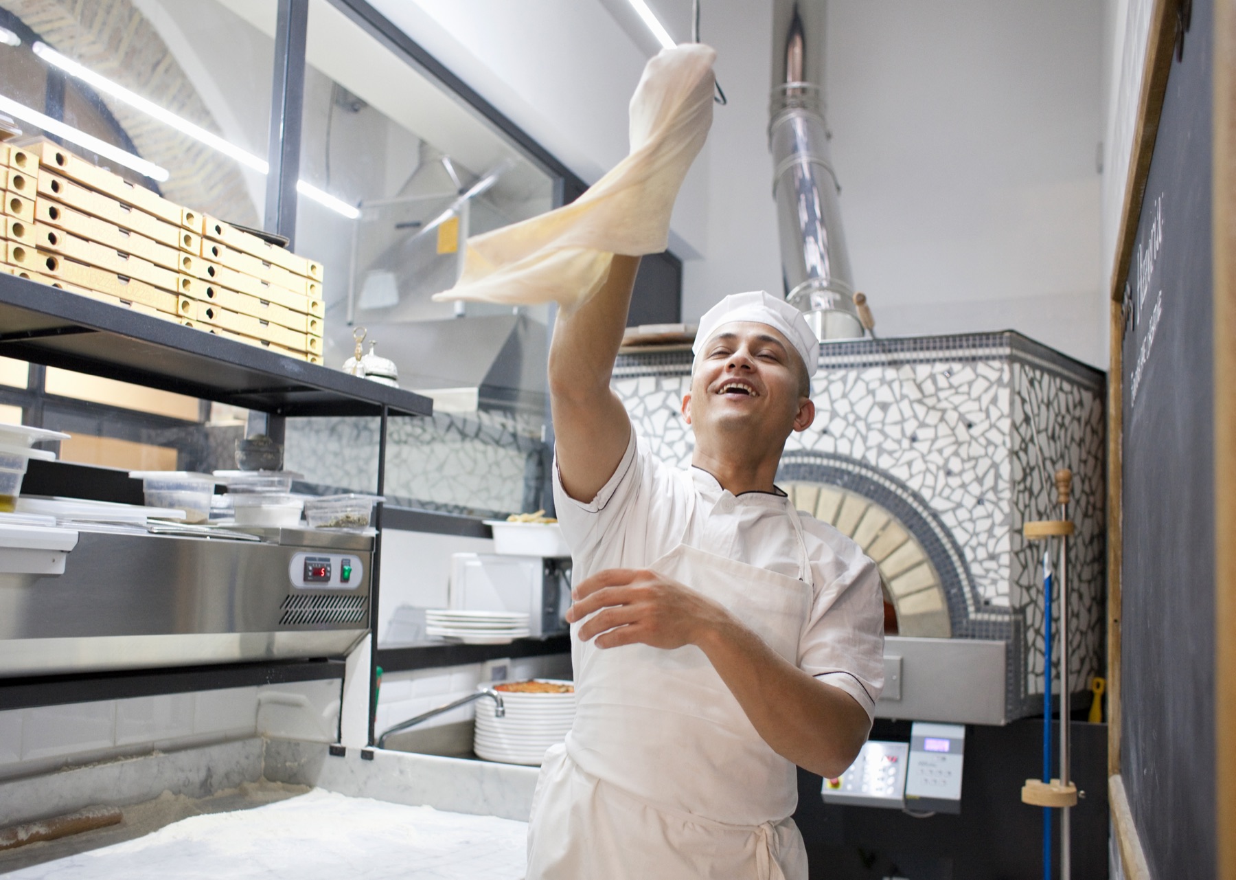 Chef tossing pizza dough in a commercial kitchen